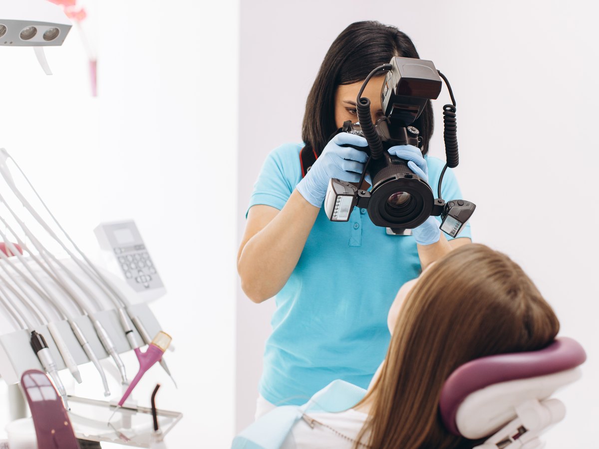 Fotos clínicas de ortodoncia: una dentista fotografía los dientes de su paciente en un sillón dental