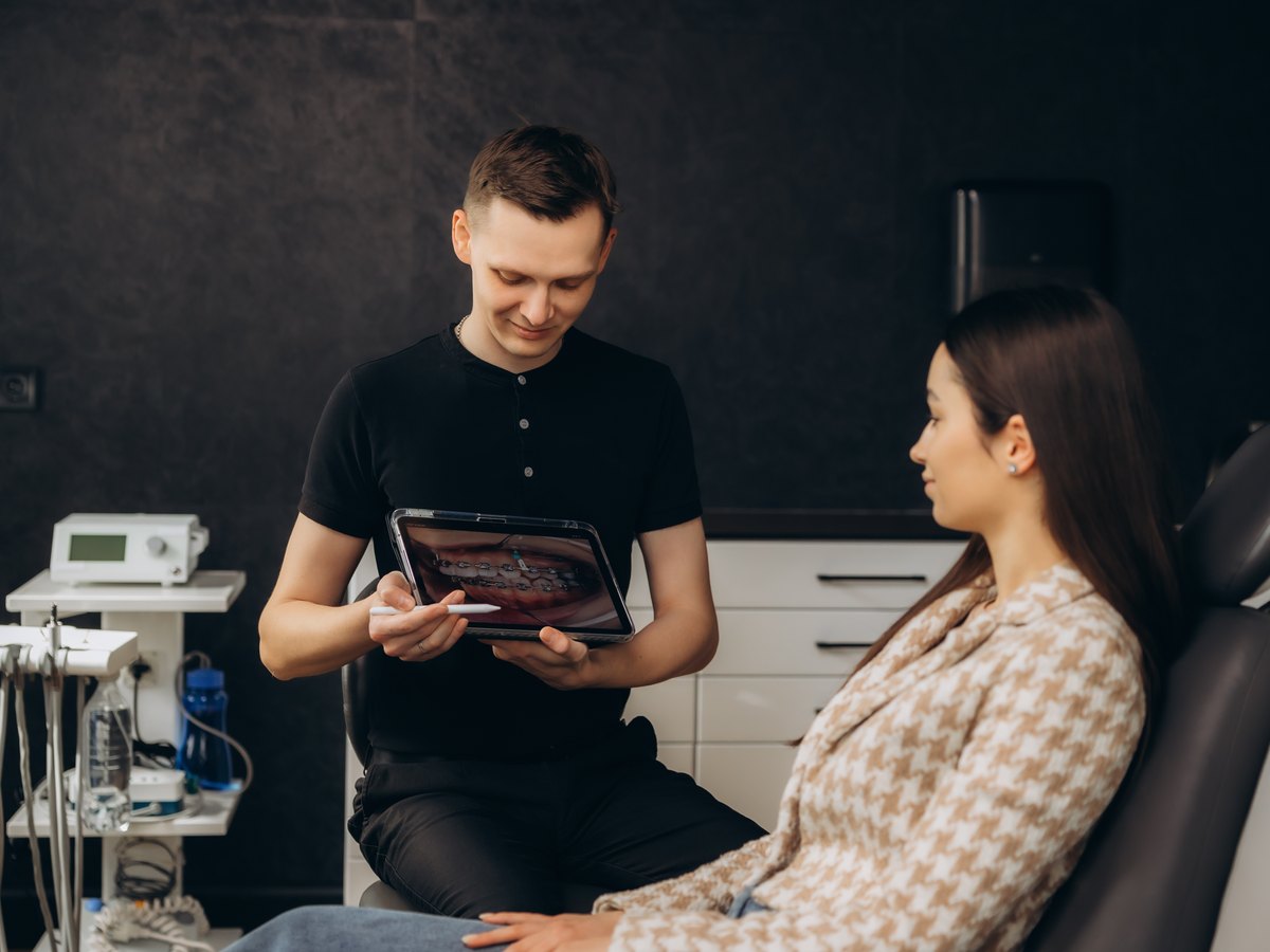 Presupuesto de los brackets de zafiro: dentista explicando el plan de tratamiento dental con una tableta digital