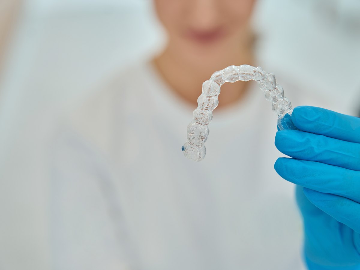 Tratamientos de ortodoncia antes y después: estomatólogo sostiene alineadores removibles invisibles para enderezar los dientes